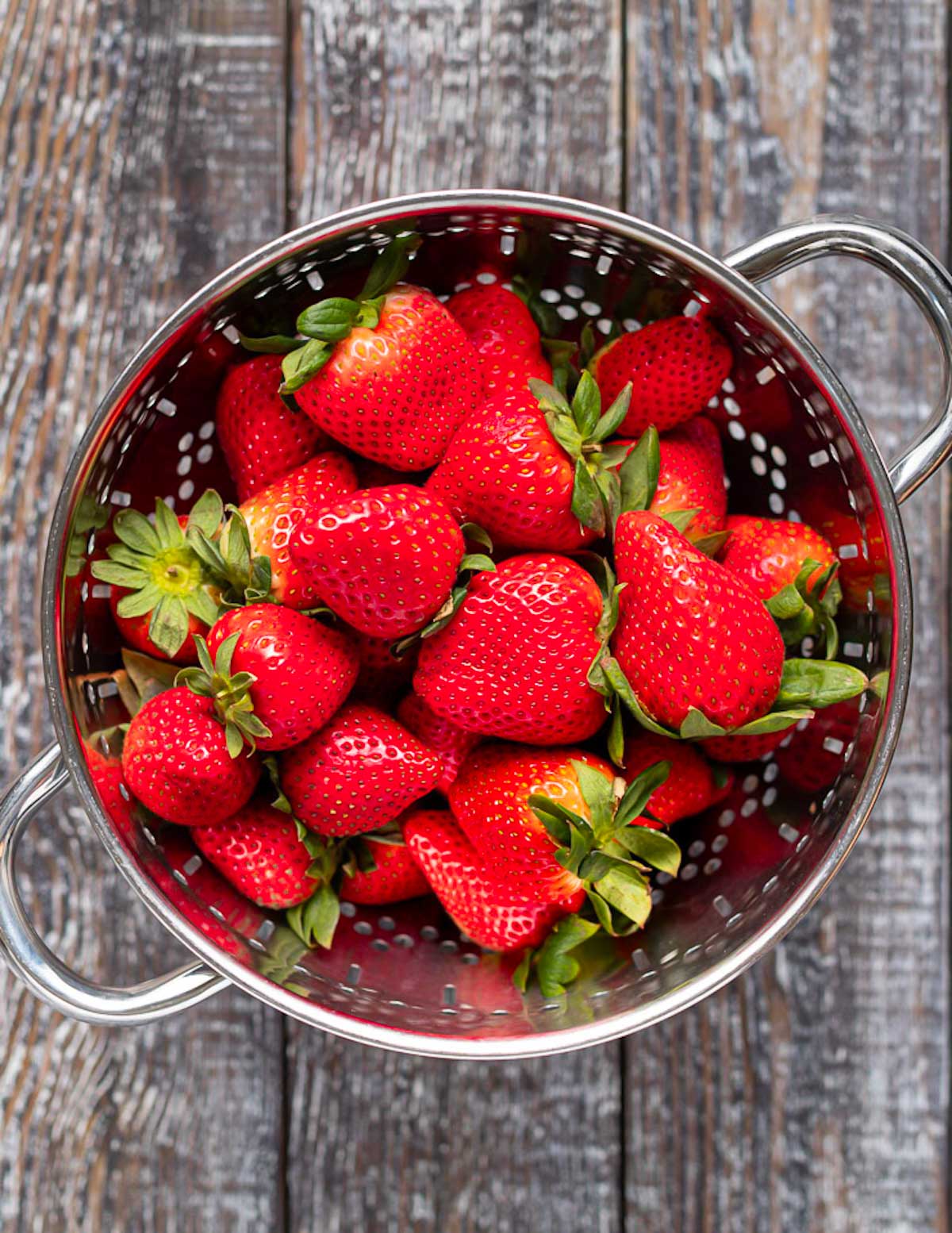 a colander full of strawberries