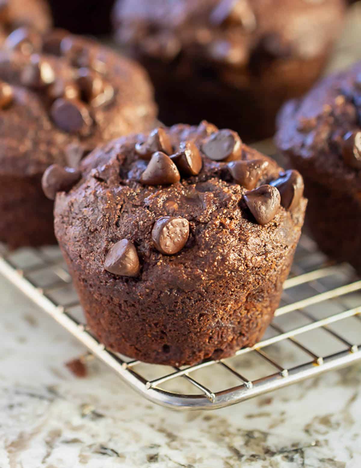 a vegan chocolate banana muffin on a wire rack