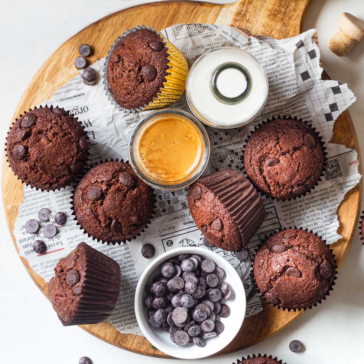 muffins on a wooden board with a bottle of plant milk, espresso and chocolate chips