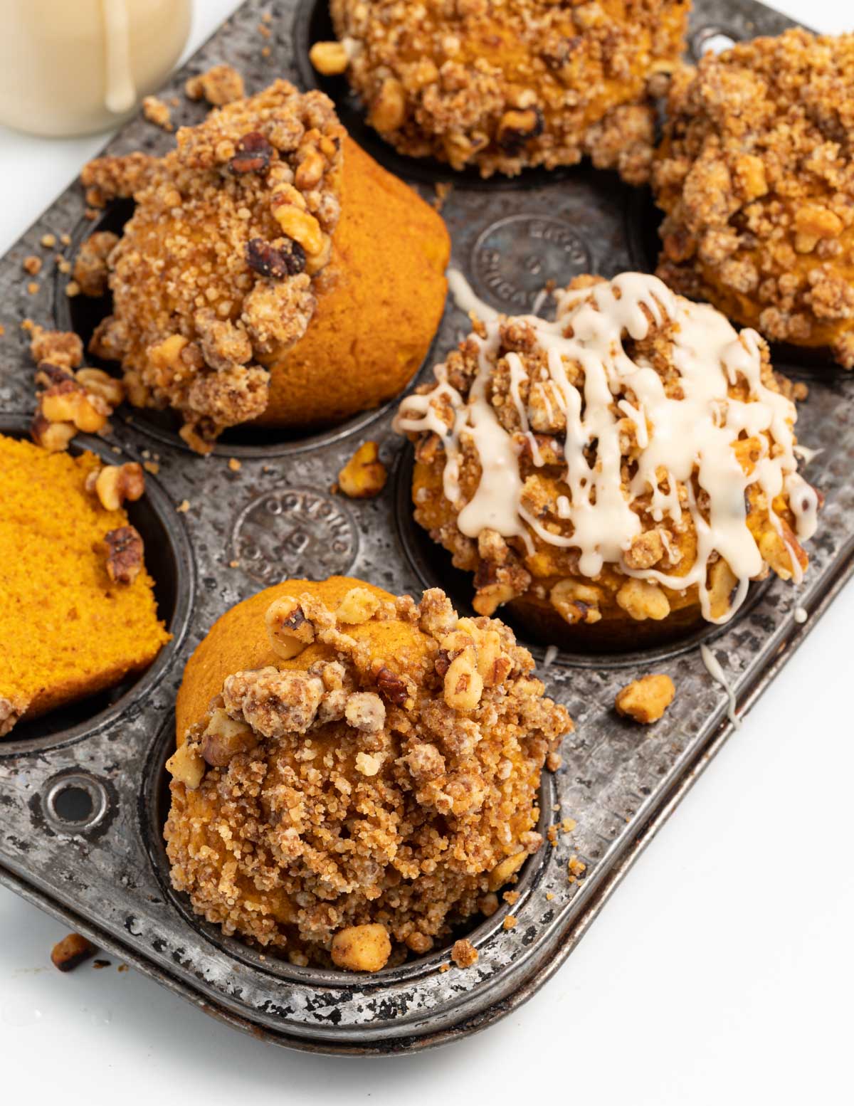 Overturned pumpkin muffins with streusel (one with glaze) in an antique pan. 