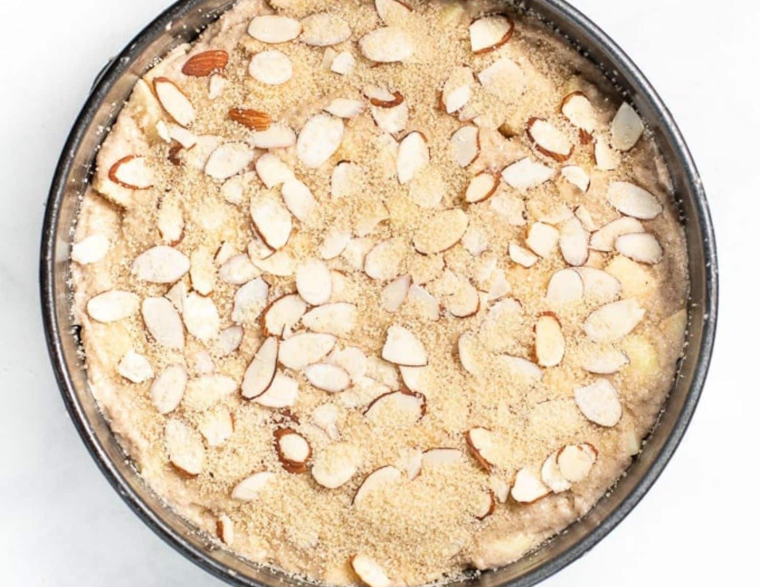 unbaked cake topped with flaked almonds and coarse sugar