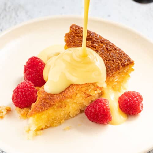 a slice of cake being drizzled with vegan custard