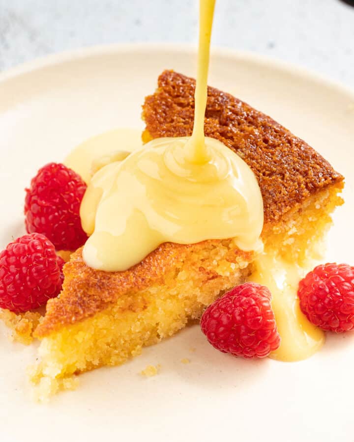 a slice of cake being drizzled with vegan custard