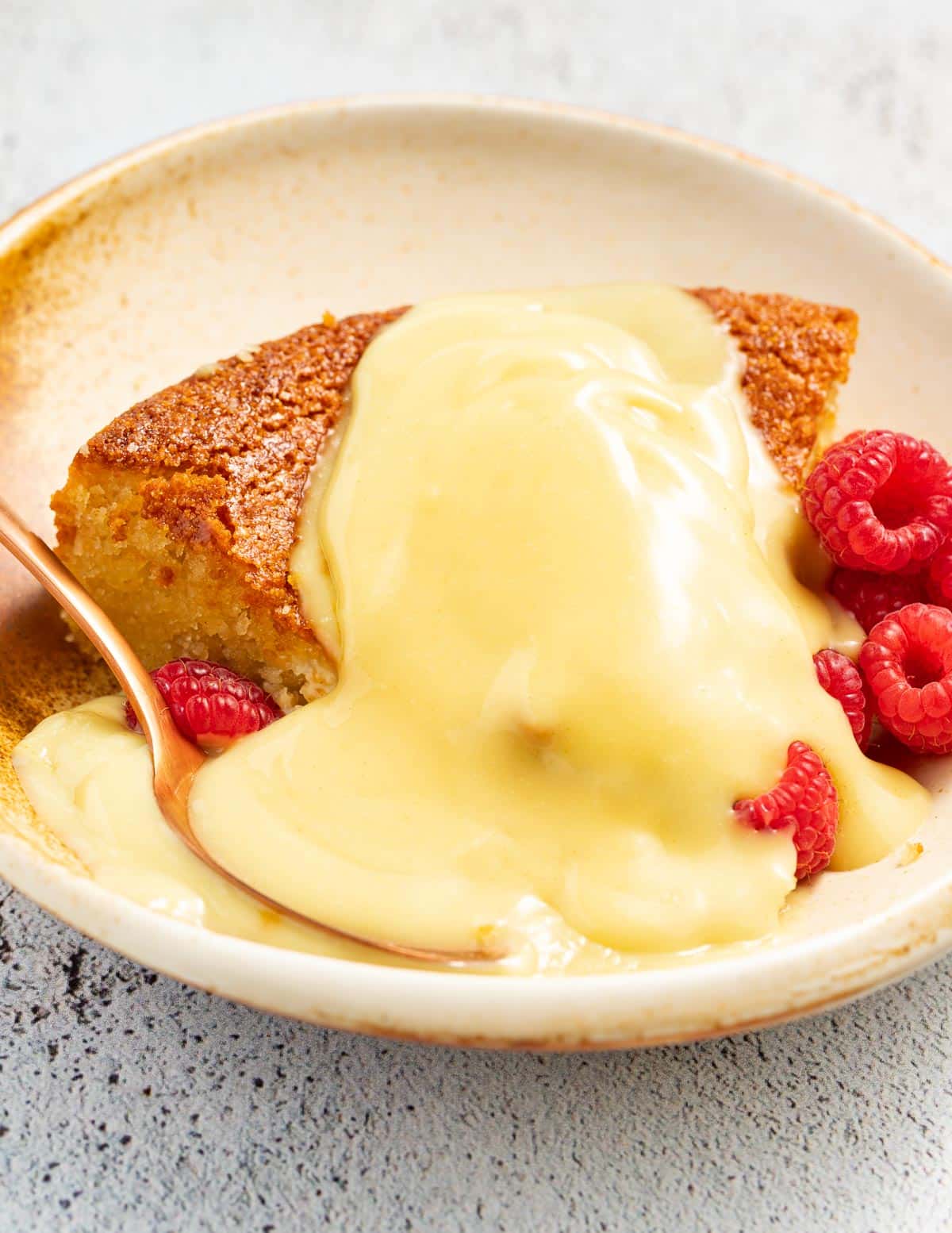 vegan custard on a slice of cake with some fresh raspberries