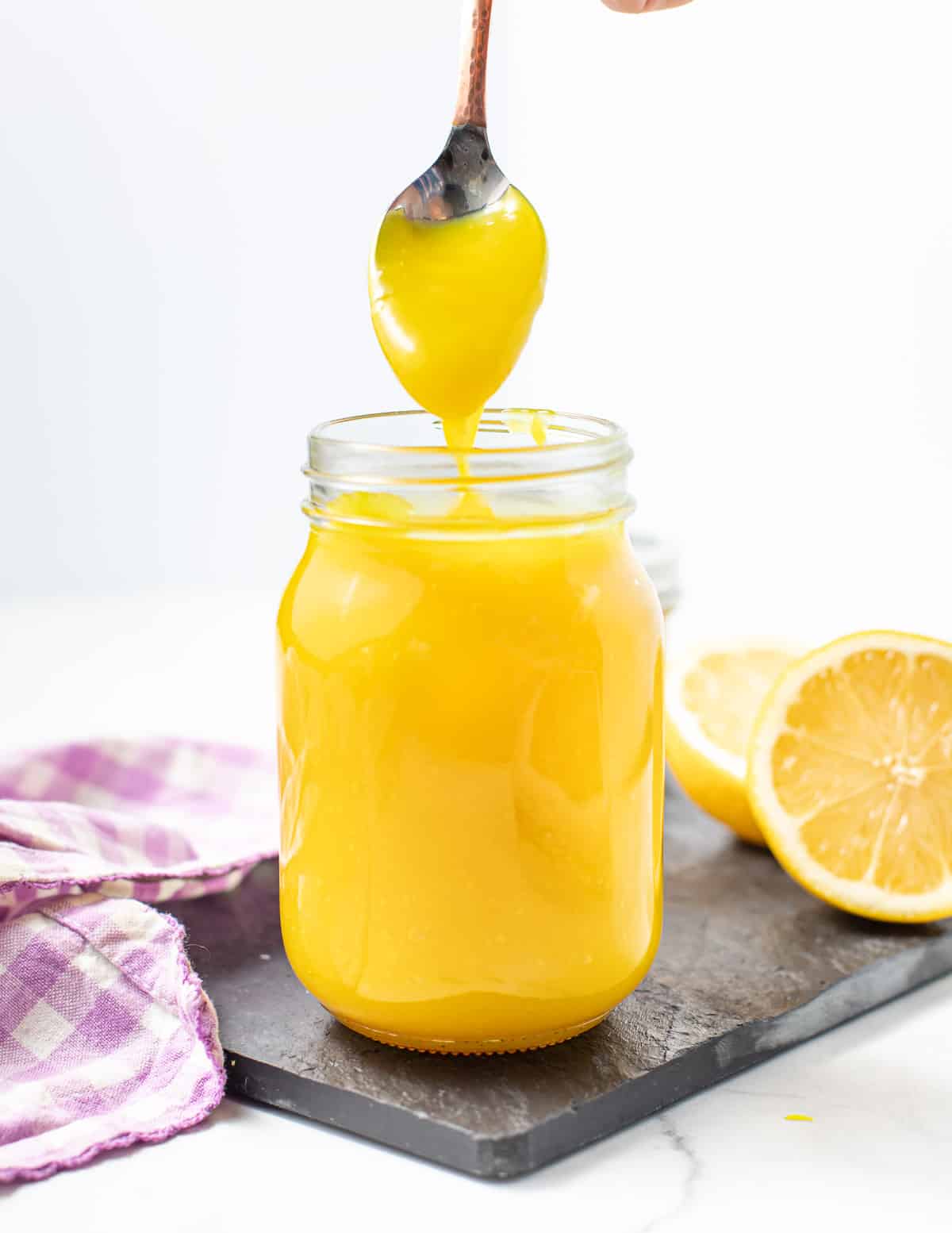 lemon curd in a jar with a drippy spoon above