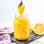 a drippy spoon above a jar of lemon curd