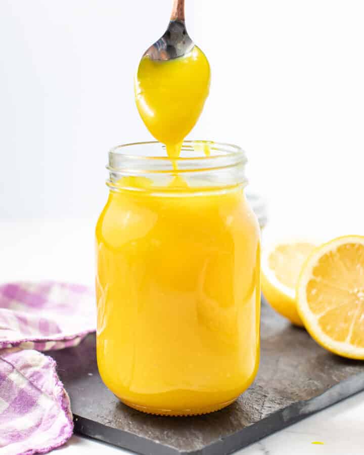 a drippy spoon above a jar of lemon curd