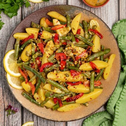 a plate of green bean potato salad with lemon slice garnish