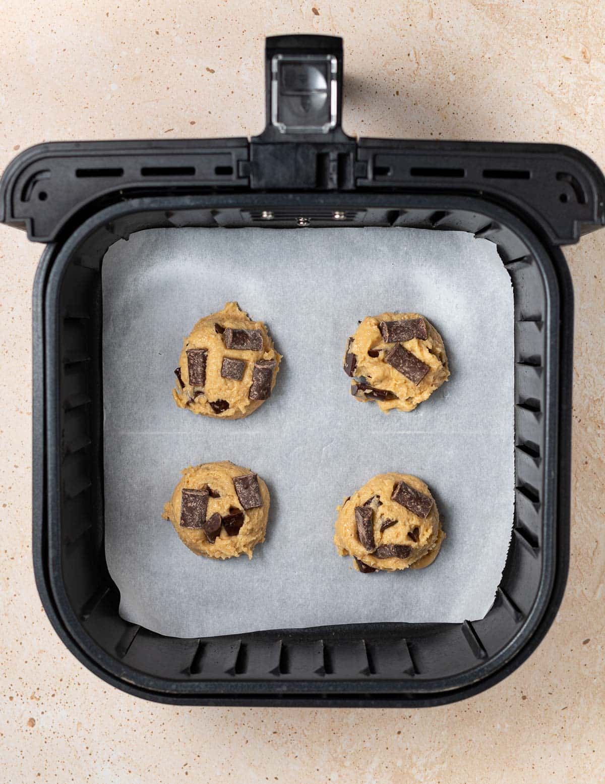 4 balls of cookie dough in an air fryer basket