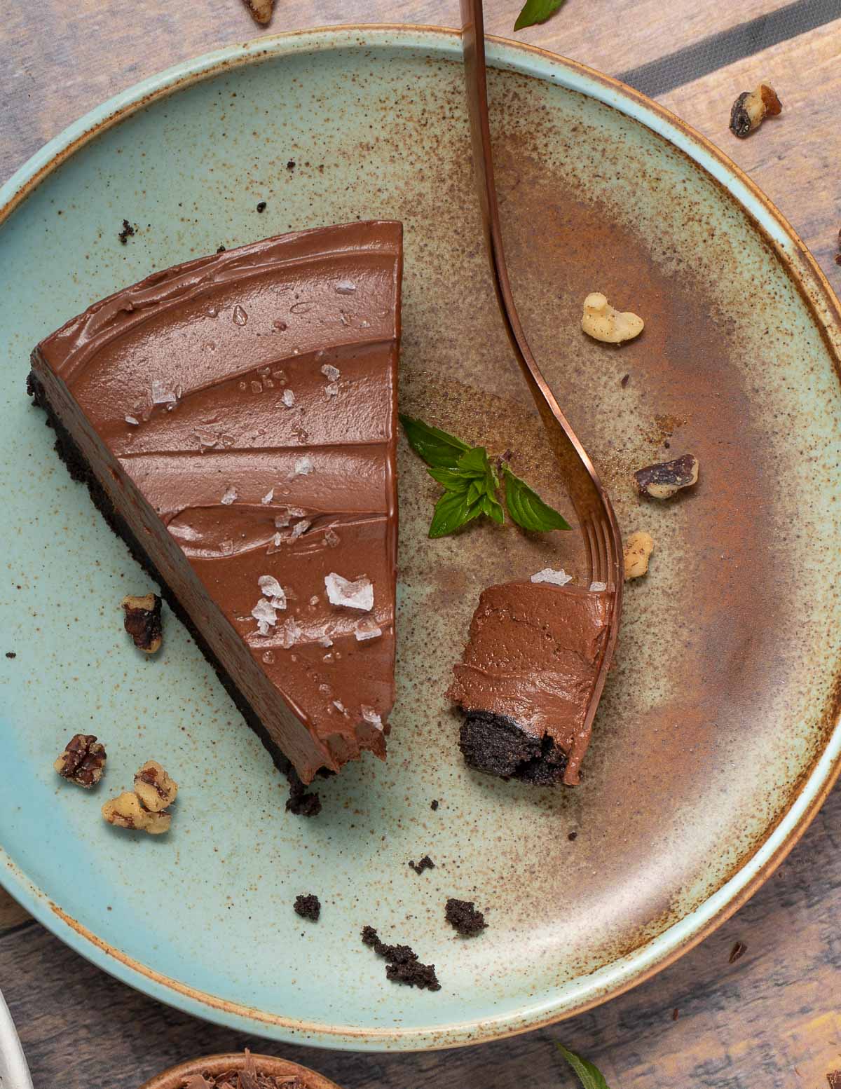 a slice of chocolate cheesecake and a fork on a blue and brown plate