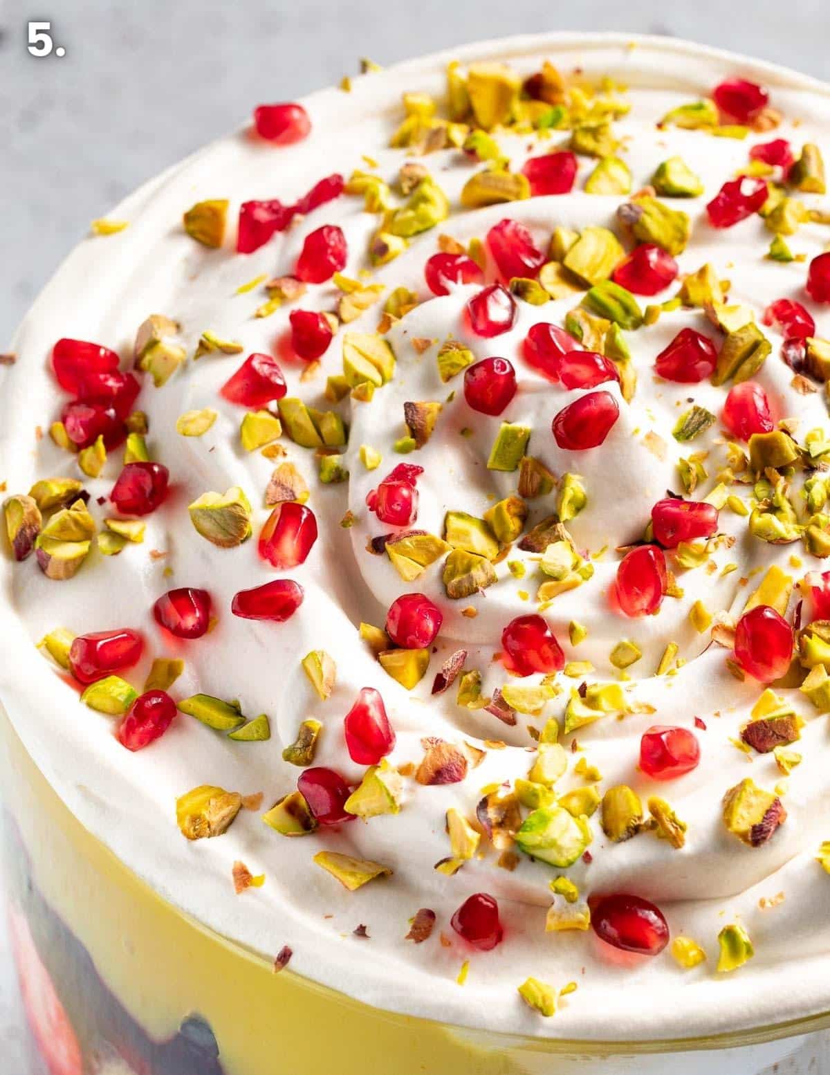 decoration on top of a trifle featuring chopped pistachio nut and pomegranate arils