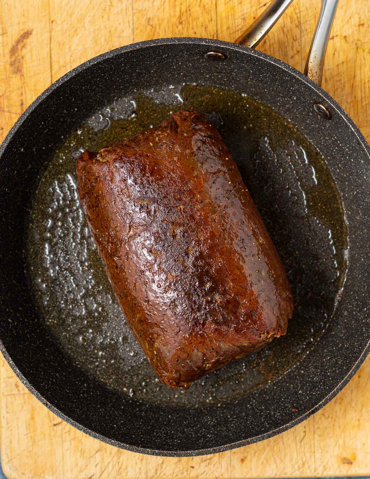 beef seitan being seared in a cast iron pan