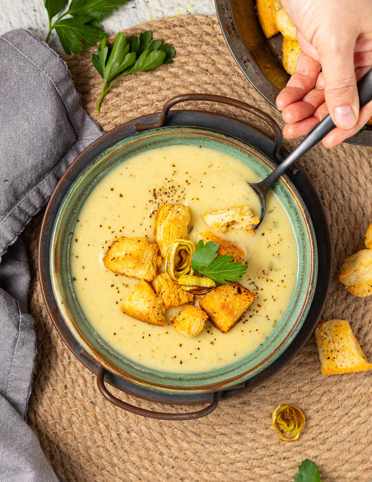 a bowl of vegan leek and potato soup with croutons