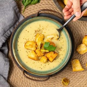 a bowl of vegan leek and potato soup with croutons