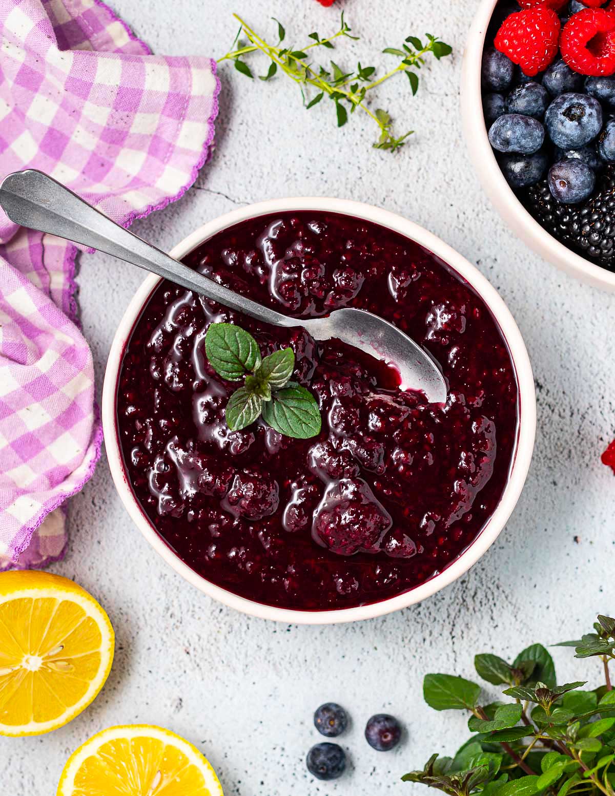 a bowl of mixed berry compote with a mint garnish 