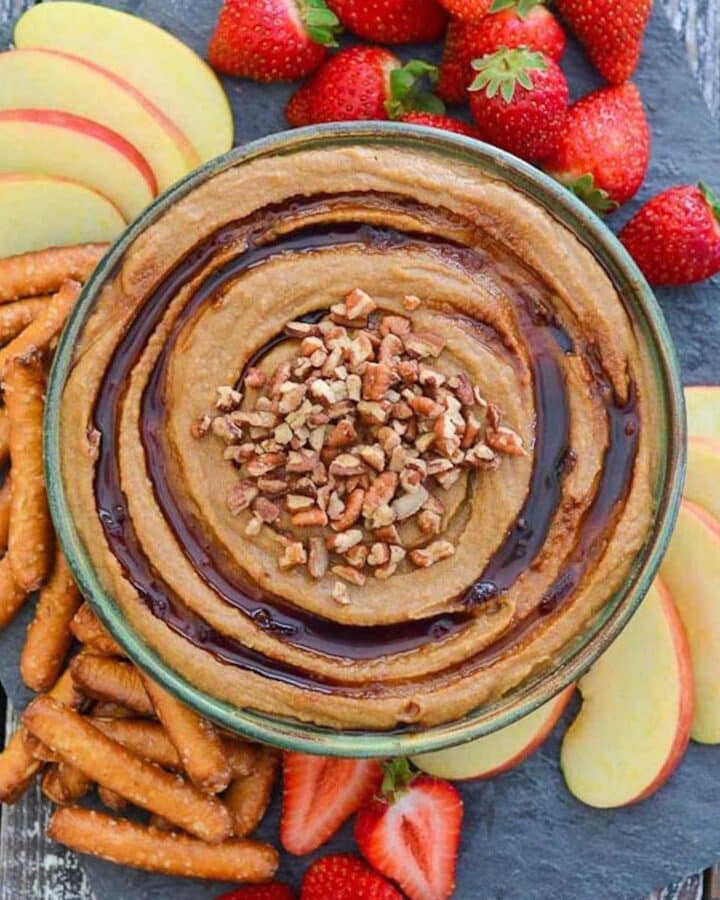 a bowl of snickerdoodle hummus with pretzels and fruit