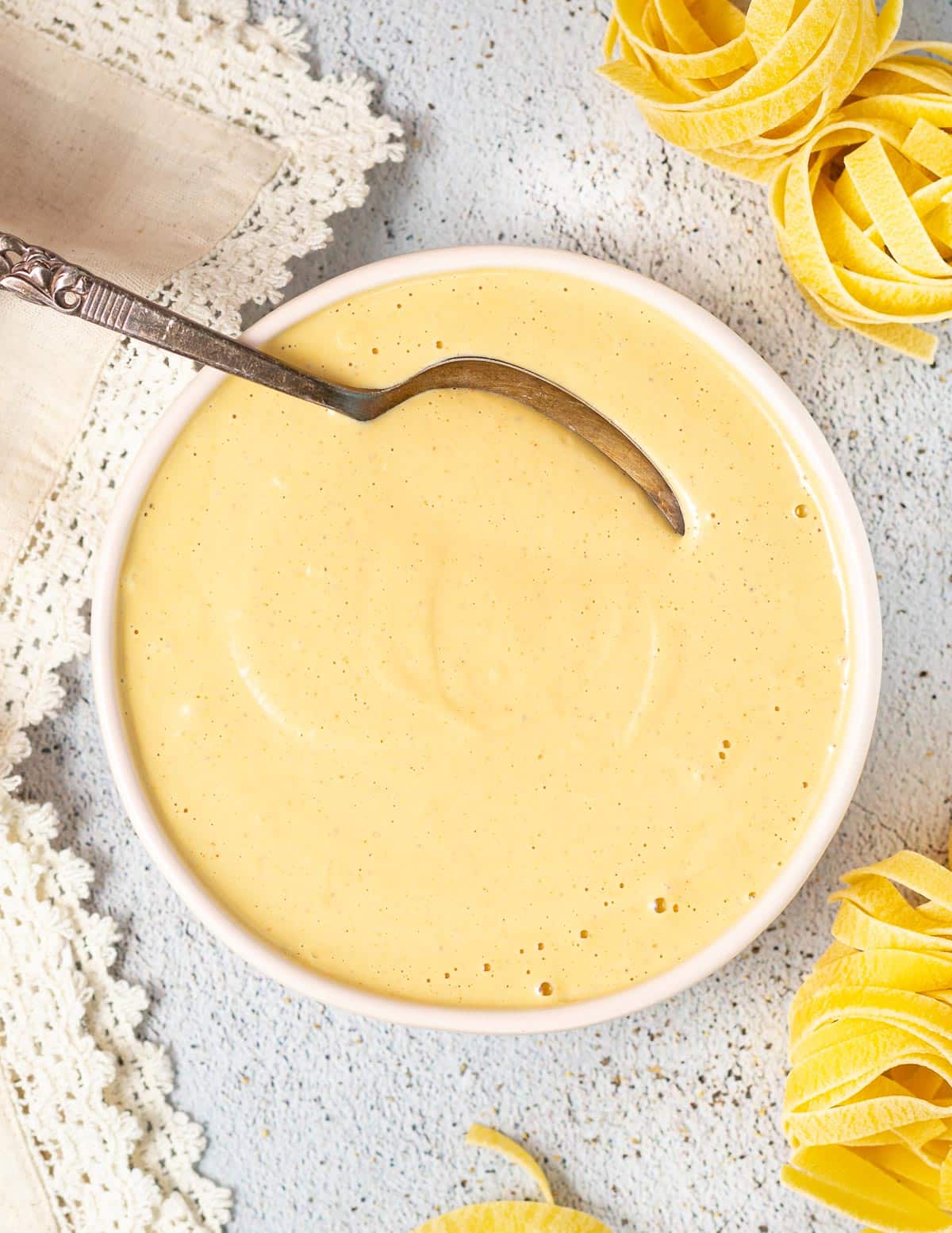 a bowl of cashew cheese sauce with a spoon on it