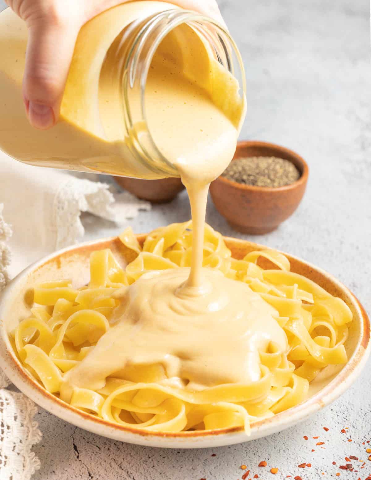 sauce being poured over fettuccine 