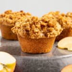 vegan apple muffins with fresh apple pieces scattered around