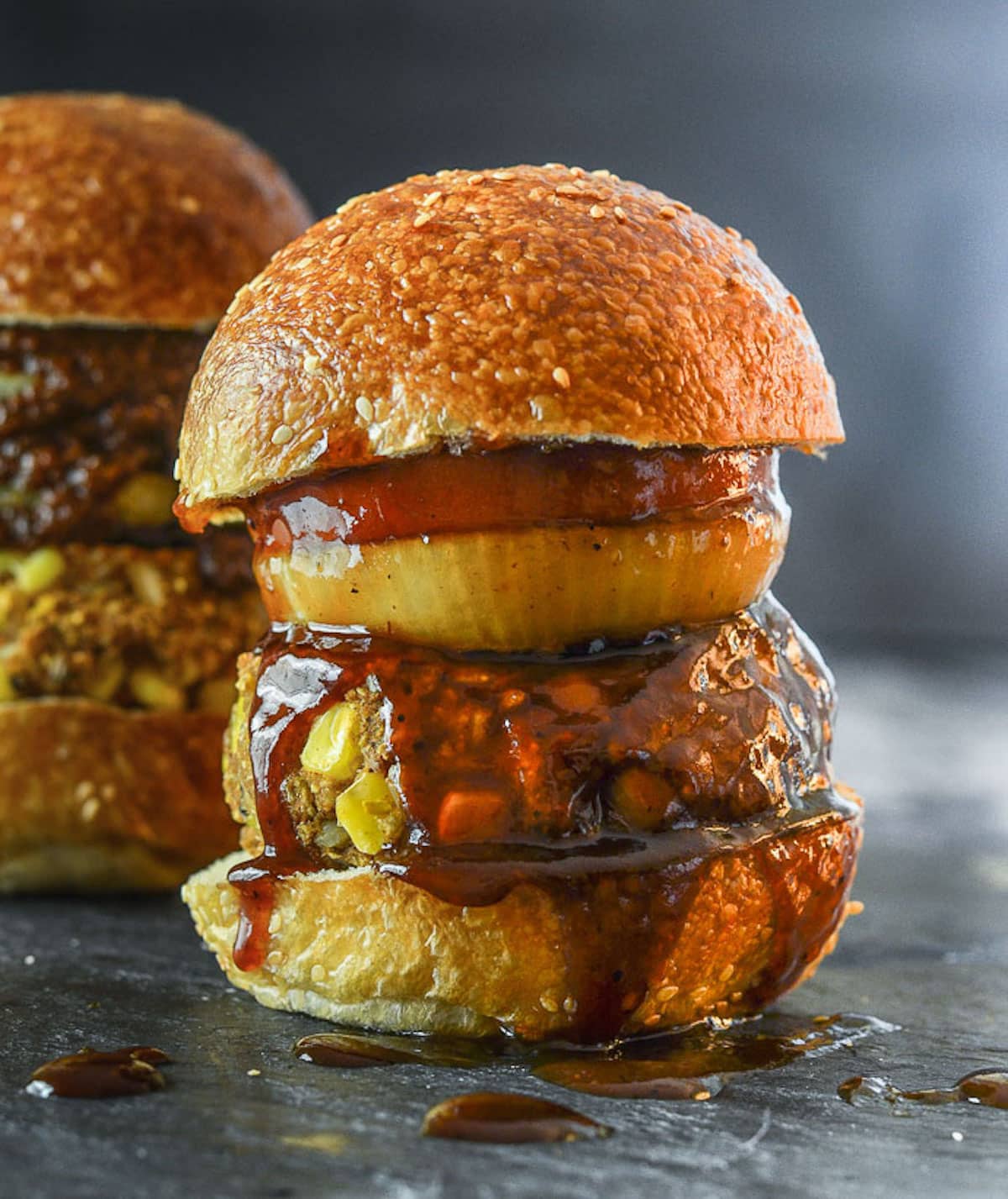 vegan BBQ burger in a bun with onion, tomato an BBQ sauce