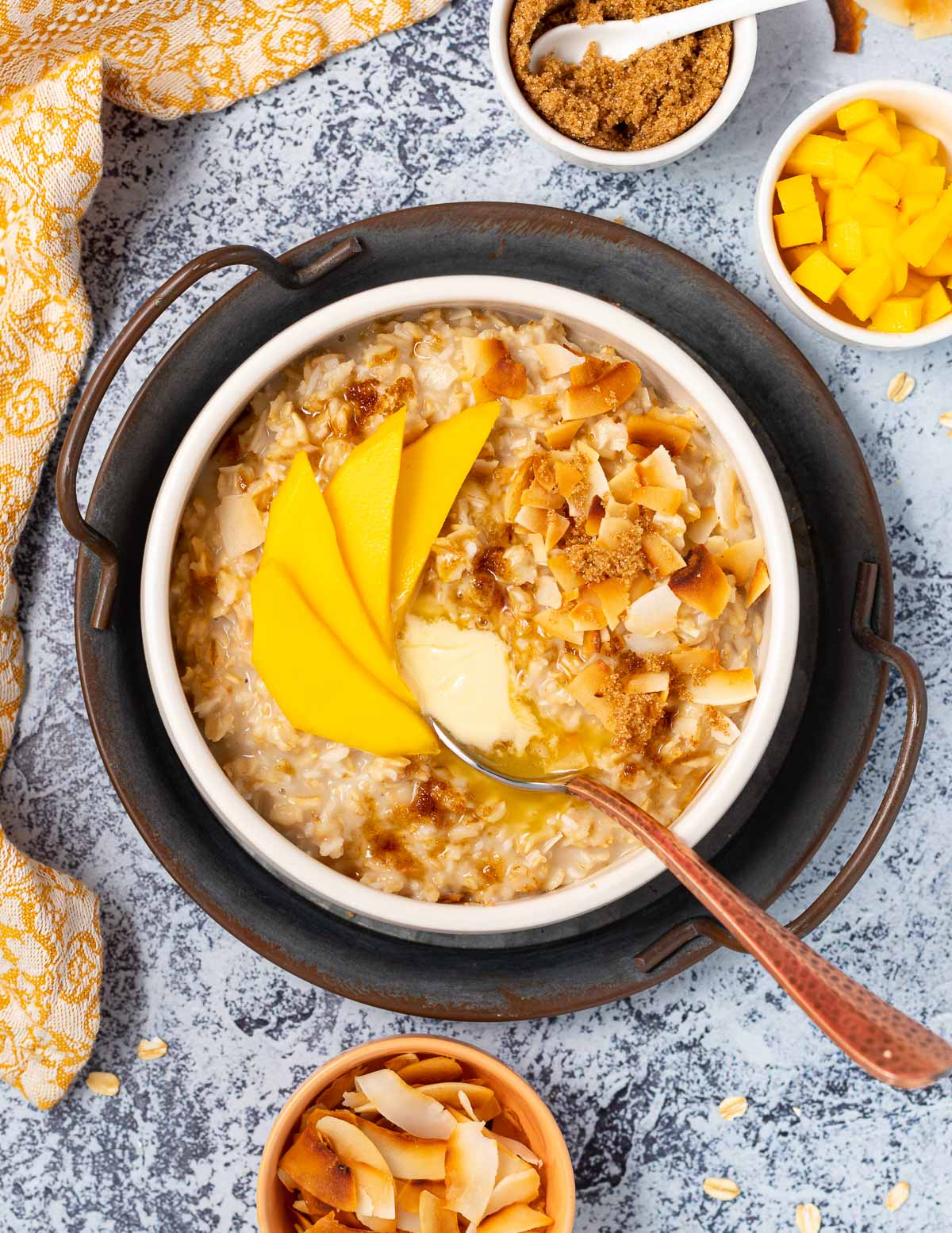 a bowl of coconut milk oatmeal topped with mango ad toasted coconut