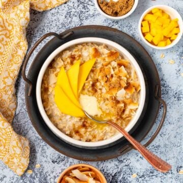a bowl of coconut milk oatmeal topped with mango