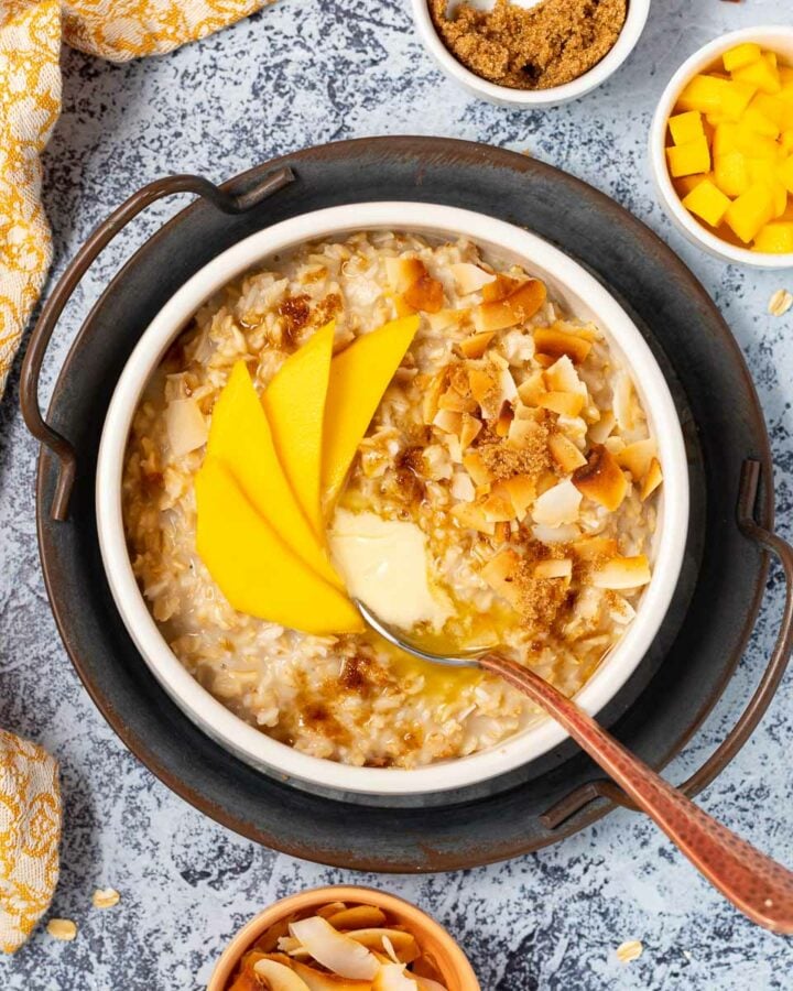a bowl of coconut milk oatmeal topped with mango