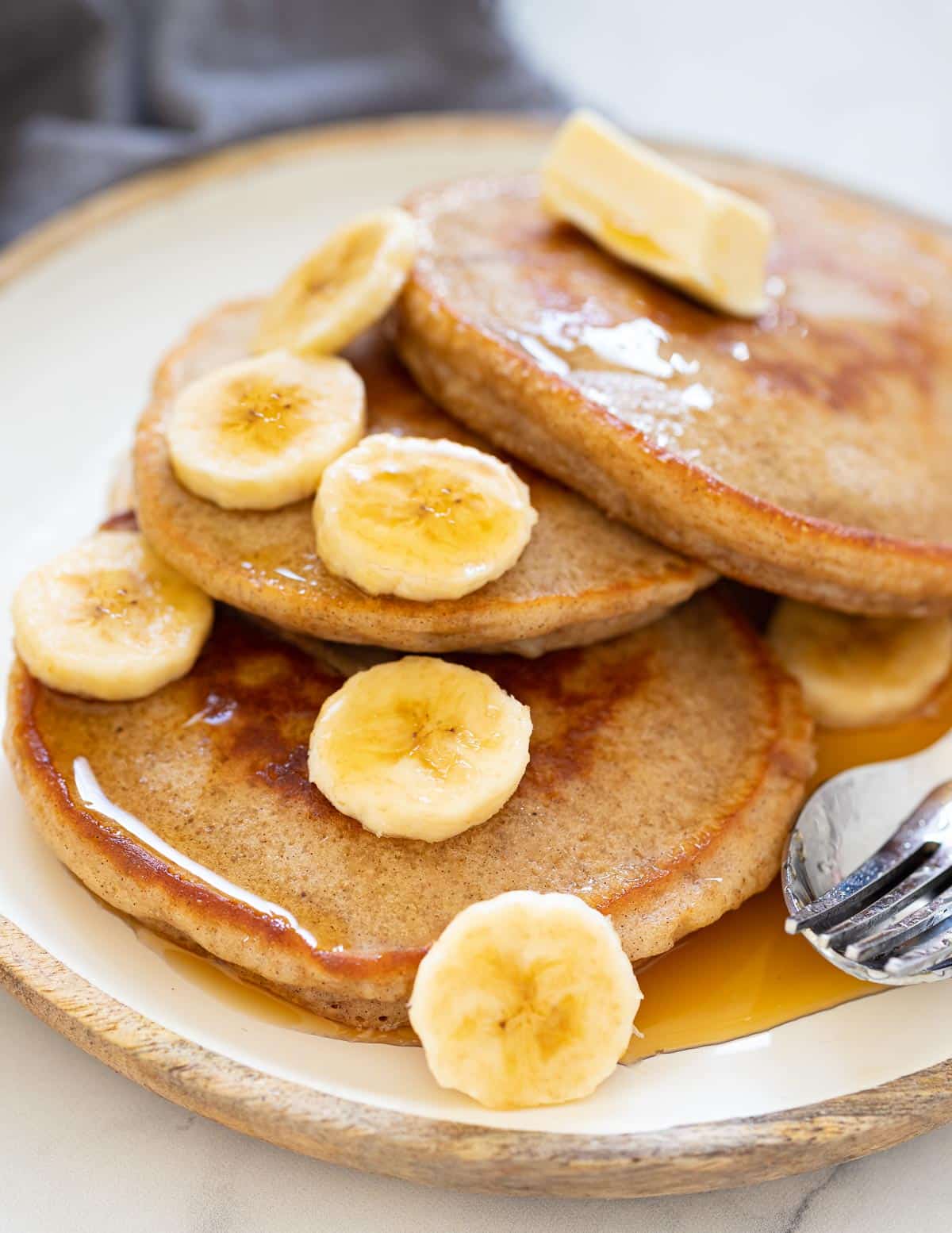 banana pancakes on a plate with slice banana and syrup