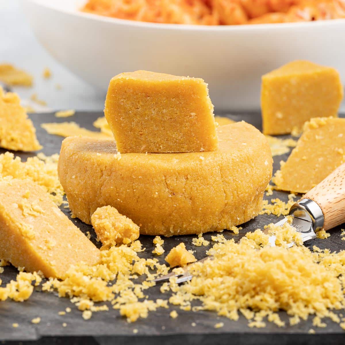 a wheel of vegan parmesan that has had wedges cut out and some grated