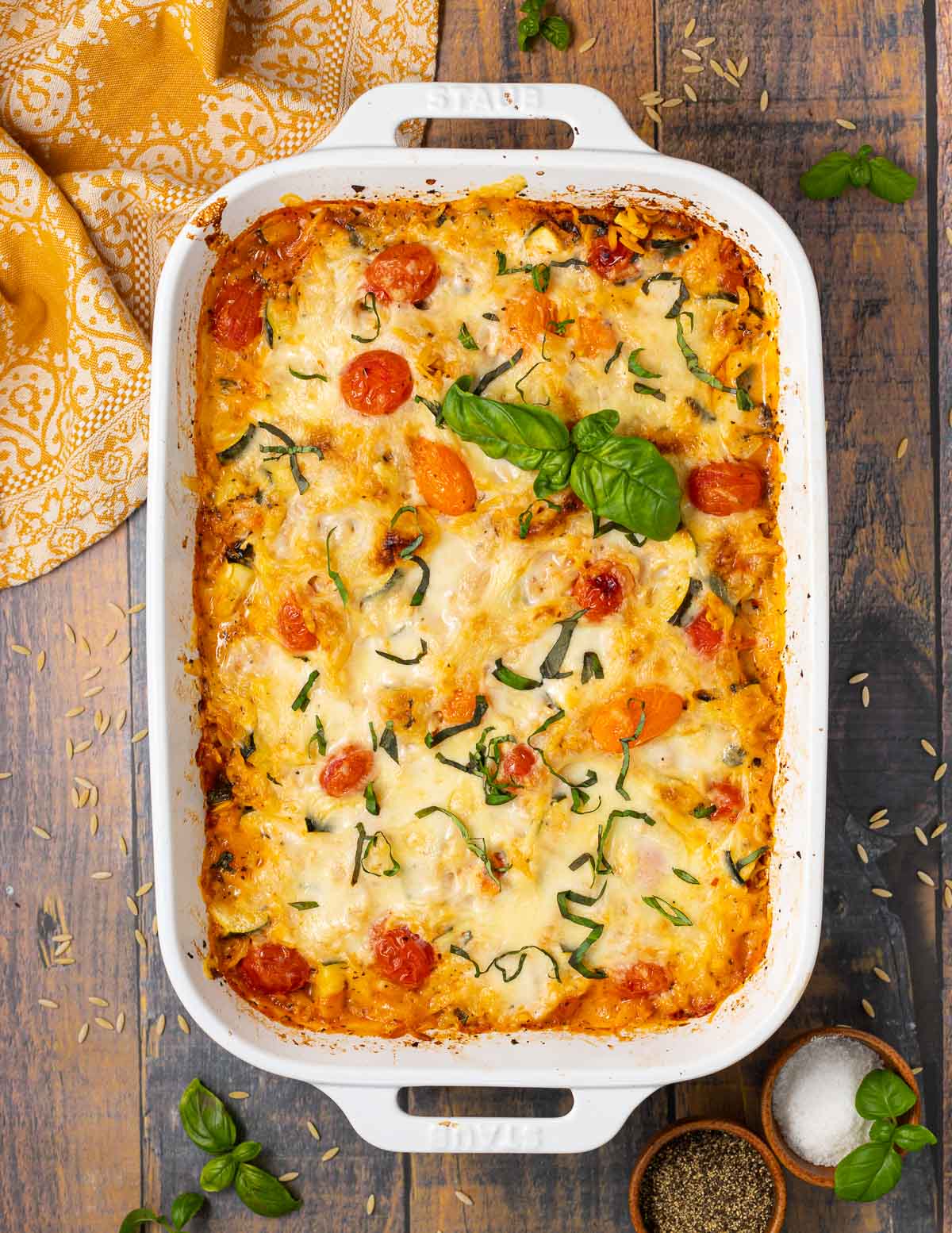 a white dish with cheesy vegan orzo topped with fresh basil 