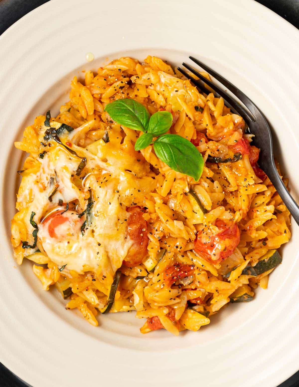 a bowl of cheesy vegan orzo with fresh basil 