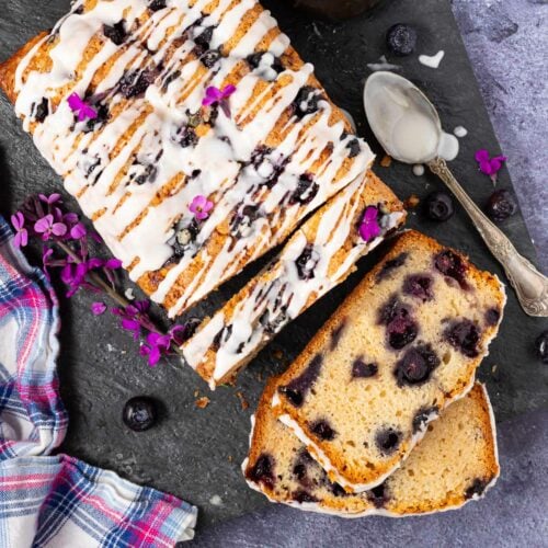 a vegan blueberry cake with 3 slices cut