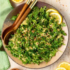 lemon orzo salad on a plate with some salad servers