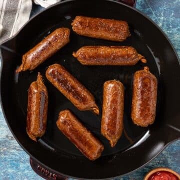 a skillet with golden vegan sausages in it