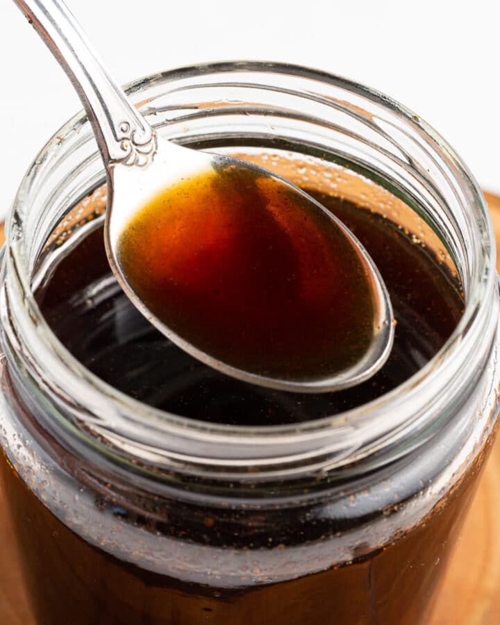 a spoonful of brown sugar syrup held over a jar of syrup