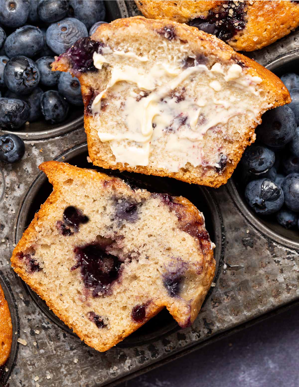 a cut blueberry muffin, one half buttered