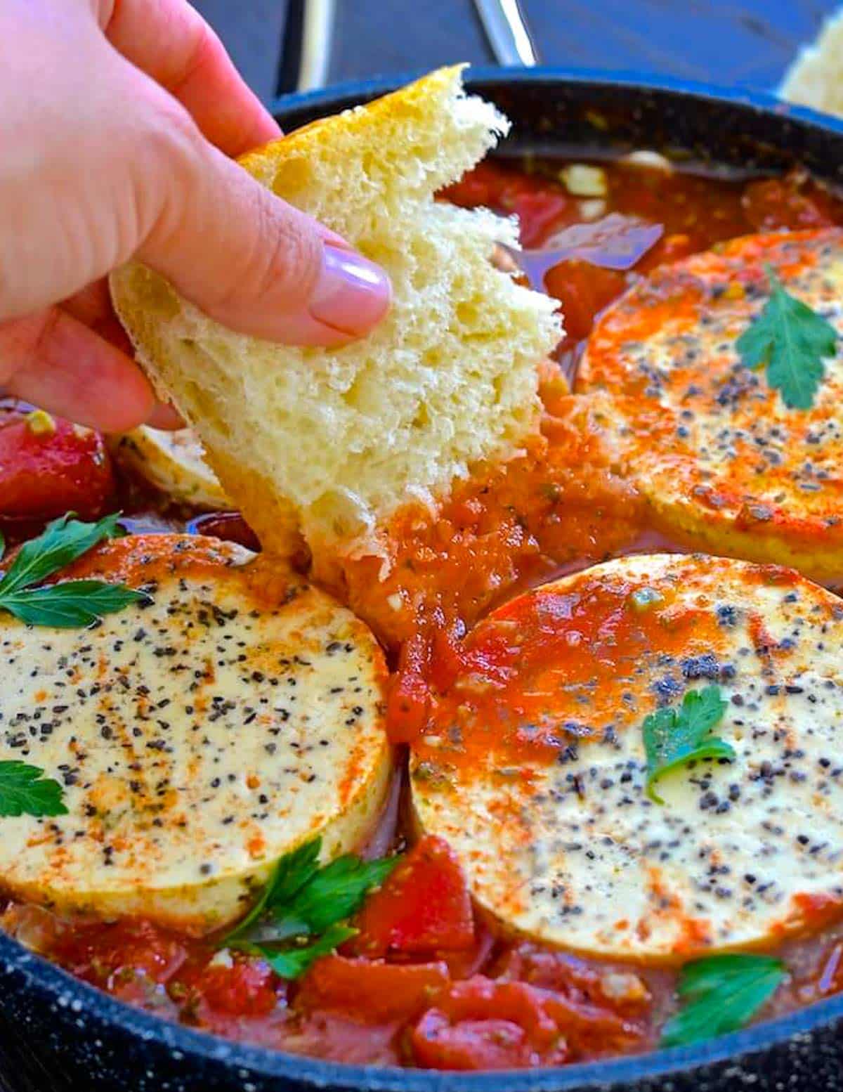 bread being dipped into shakshuka