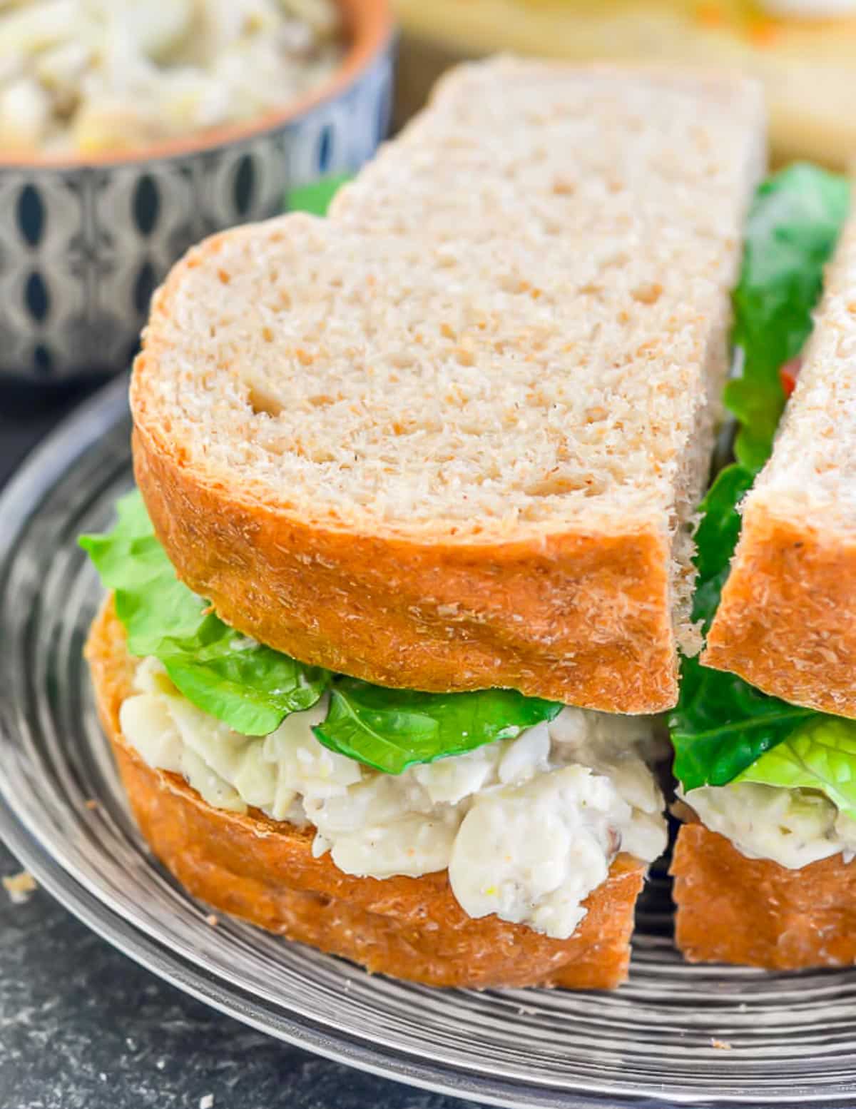 a wholewheat sandwich with vegan sandwich filling and lettuce on a black and white plate 