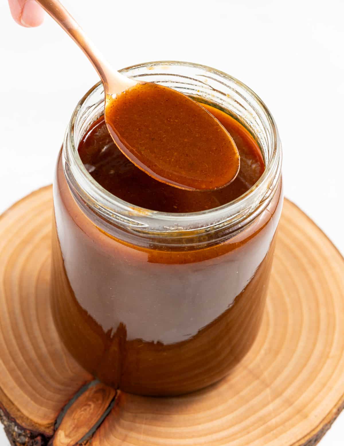 a spoonful of pumpkin spice syrup held over a jar of syrup