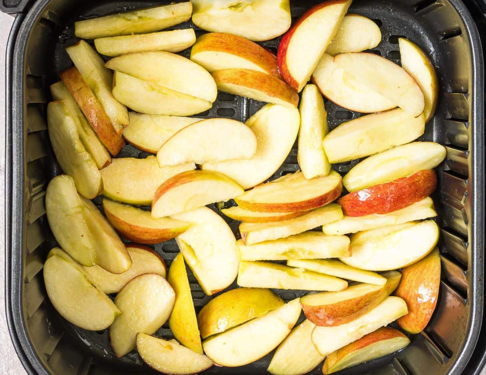 apple slices in an air fryer basket