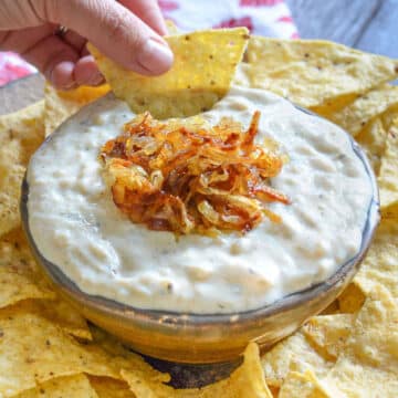a bowl of onion garlic dip with tortilla chips