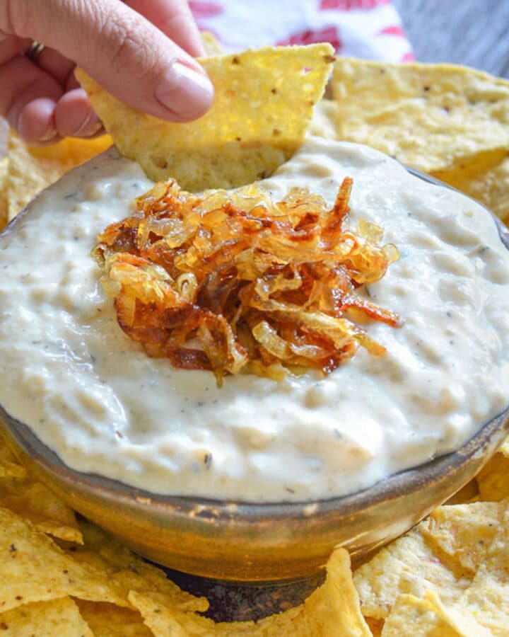 a bowl of onion garlic dip with tortilla chips