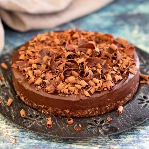 a no bake chocolate cake covered in chocolate curls on a black metal plate