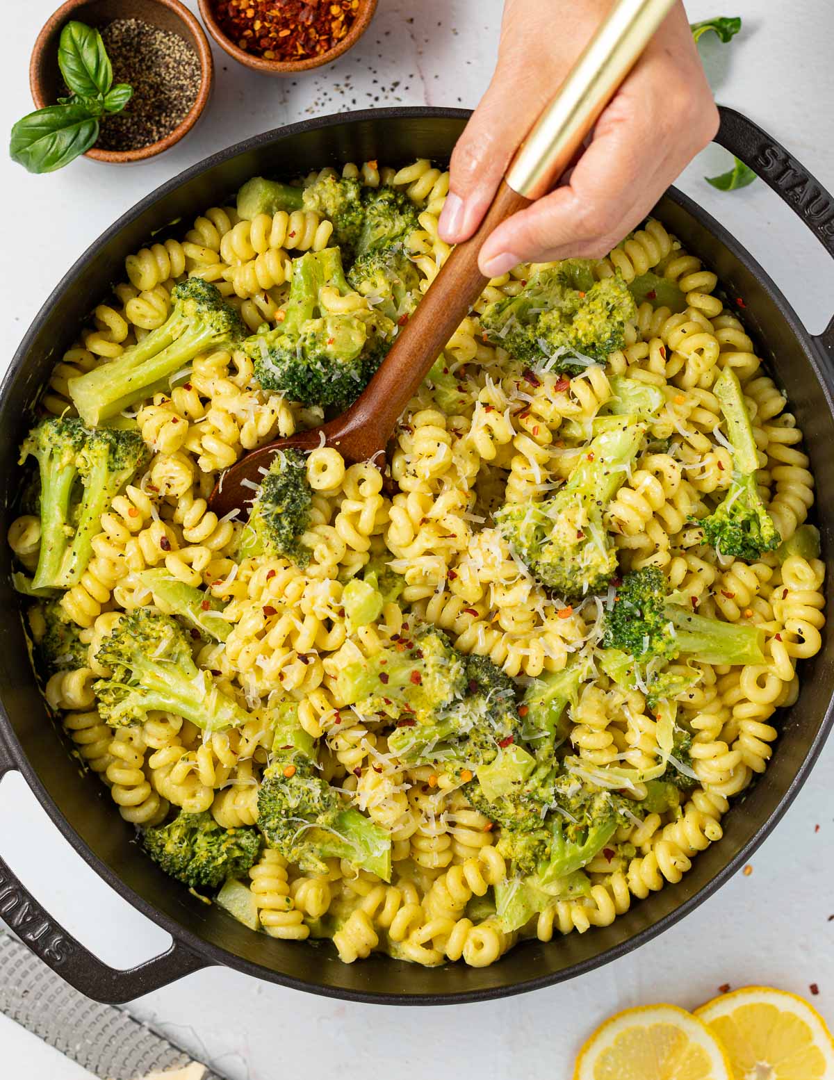 a wooden spoon digging in to a skillet full of vegan broccoli pasta