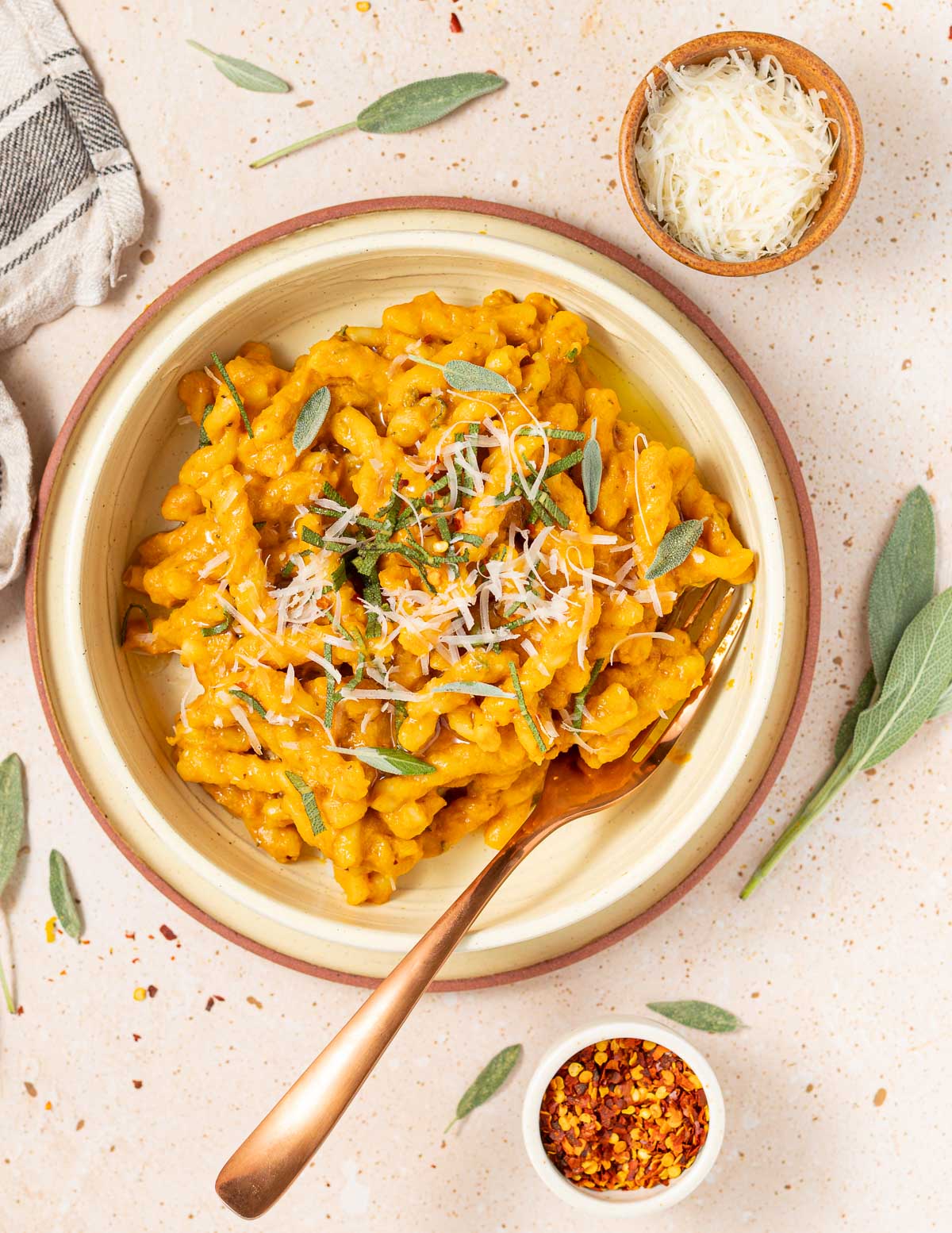 a bowl of pasta with vegan parmesan and shredded sage garnish 