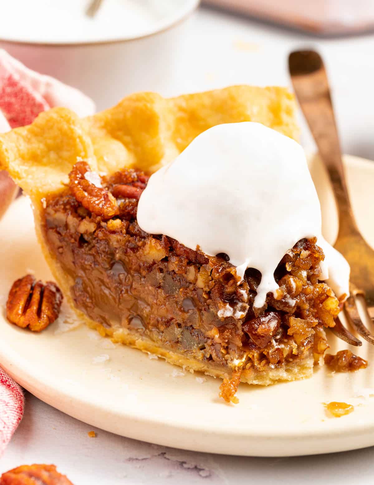 a slice of vegan pecan pie  and a dollop of cocowhip, with a bite taken from the end