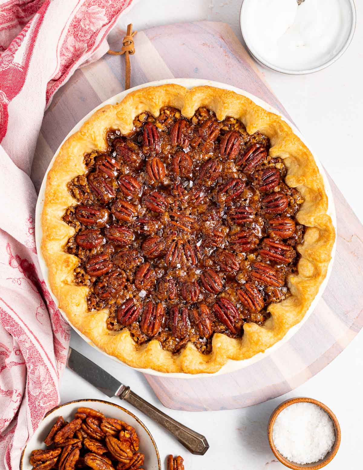 vegan pecan pie on a pink board with a pink tea towel 