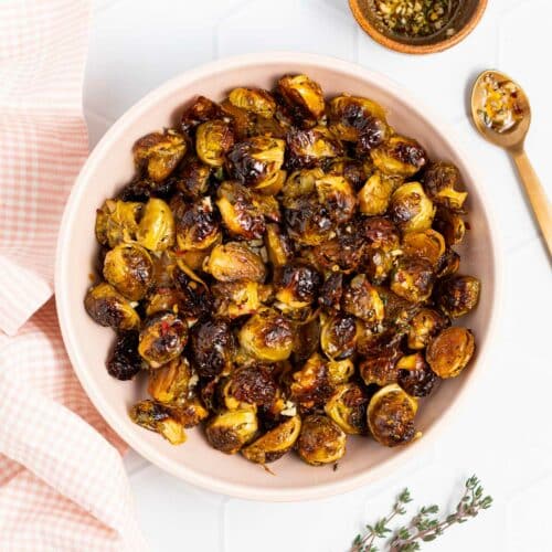 a bowl of brussels sprouts with a small bowl of dressing