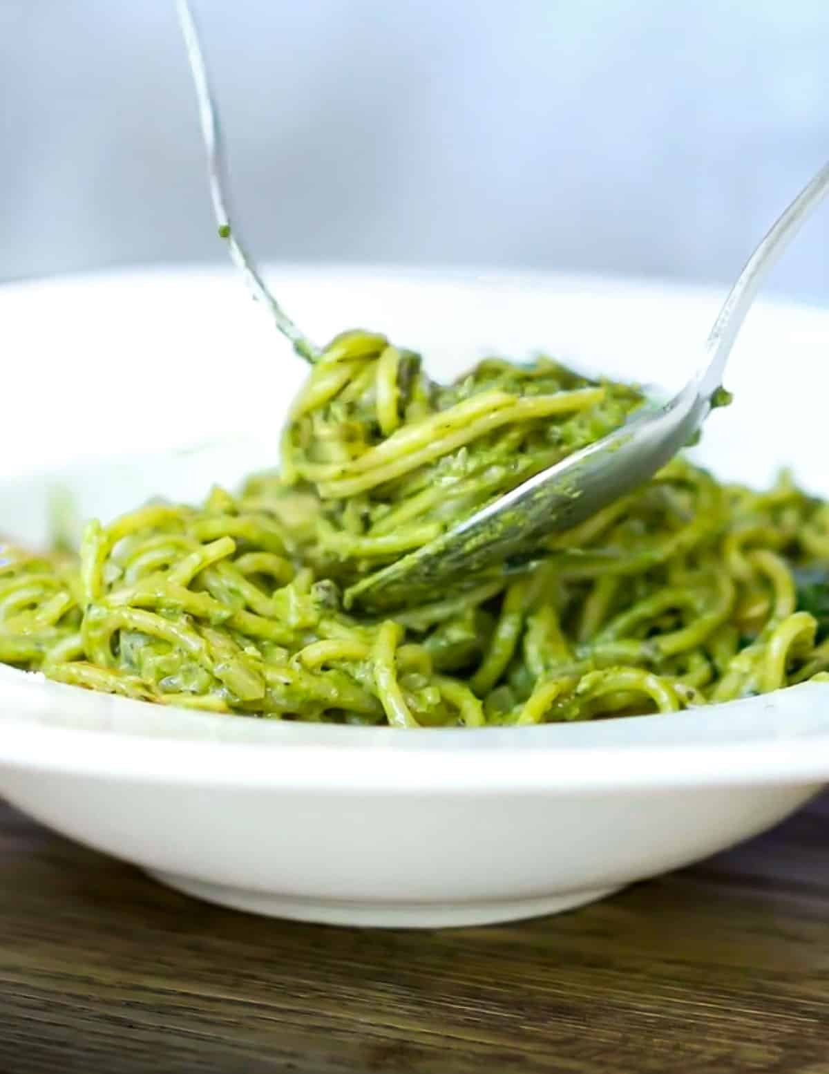 a bowl of spaghetti tossed in kale pesto