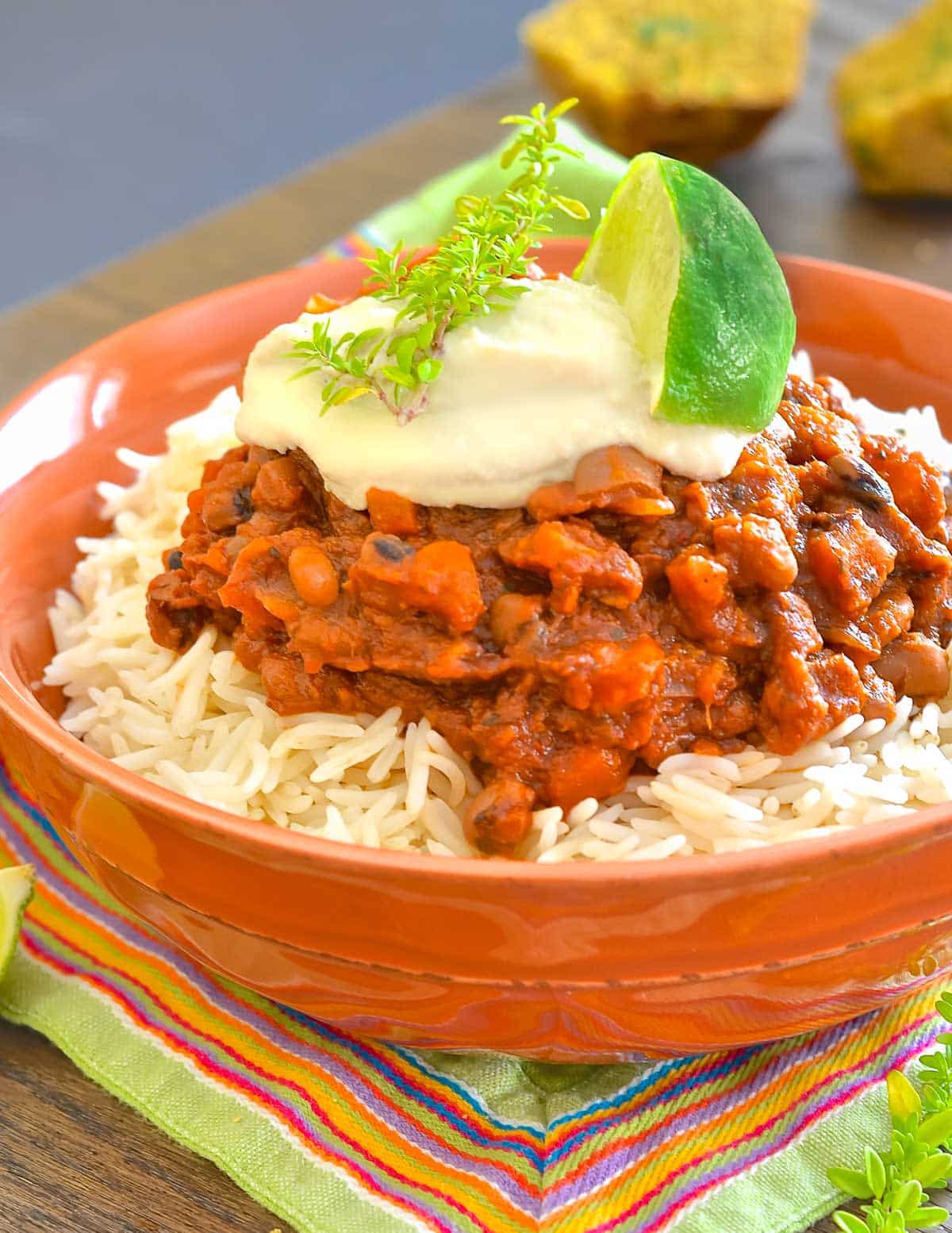 a bowl of vegan slow cooker chiliwith vegan sour cream and lime